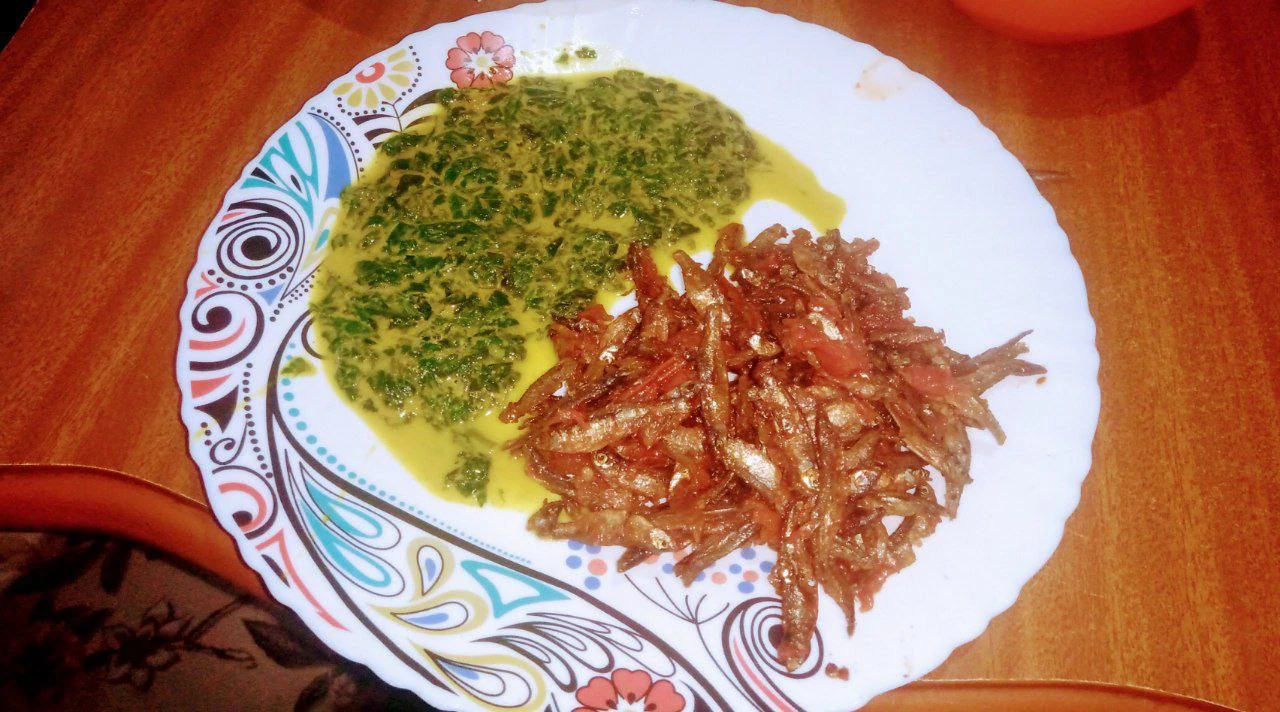 A Kenyan meal with leafy vegetables and small fish